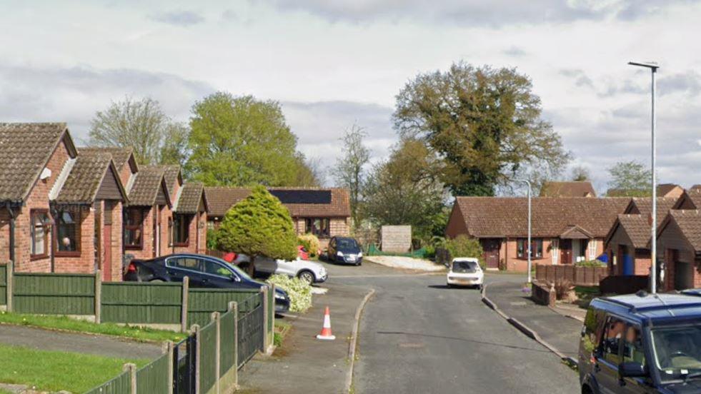 A small cul-de-sac with bungalows on both sides and a number of cars parked outside