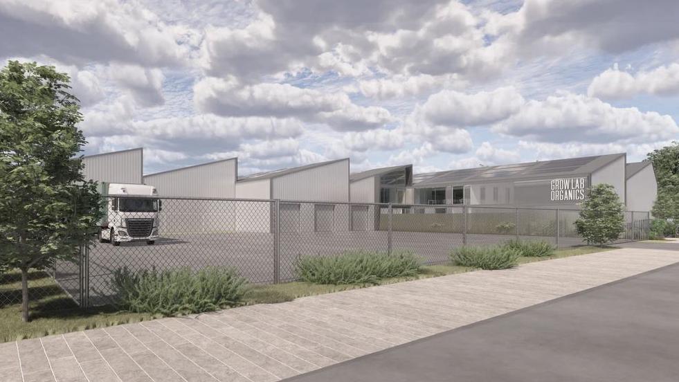 An artist's impression of the approved facility showing a large car park surrounded by a fence. Behind it are a series of buildings with angular roofs. One has a sign which reads GrowLab Organics.