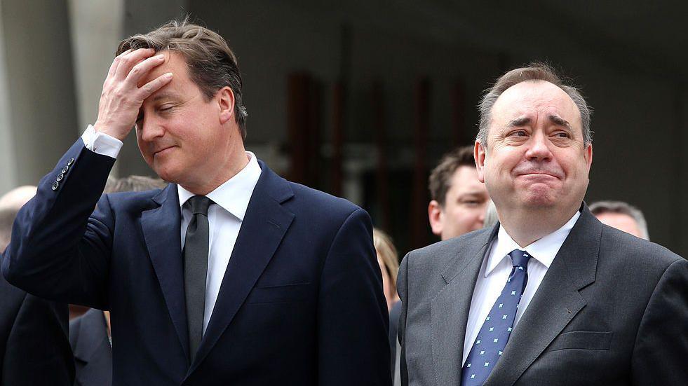 An image from 2011 of then prime minister David Cameron (a man with dark hair in a dark suit, with his hand on his head) standing next to then first minister Alex Salmond (also a man with dark hair in a dark suit, but with a faintly amused expression)