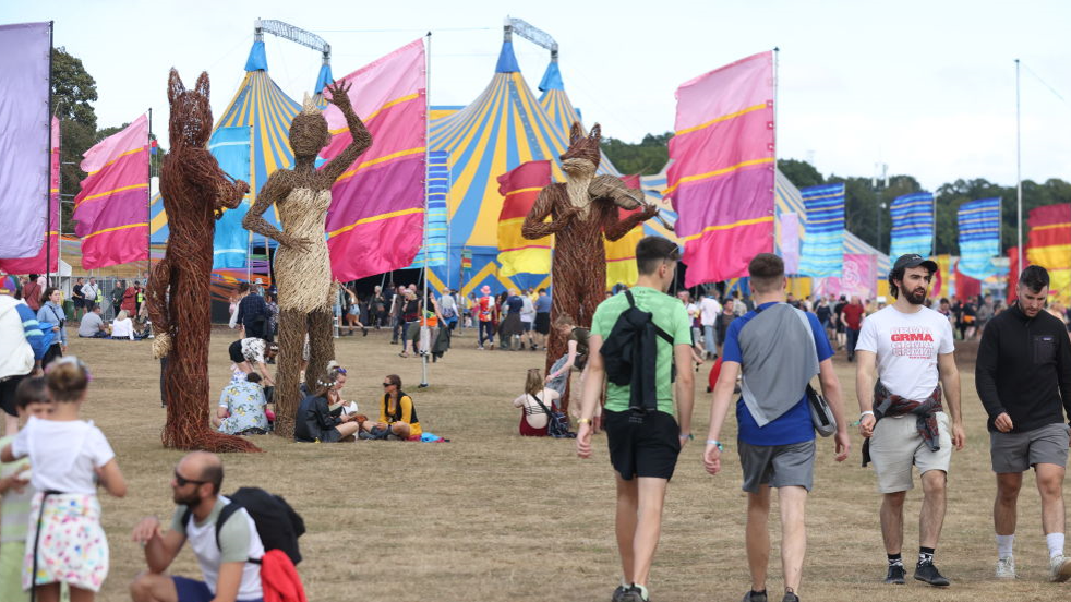 A group of people walking around the Electric Picnic site in 2022 with large wicker fox structures and tents and flags around them