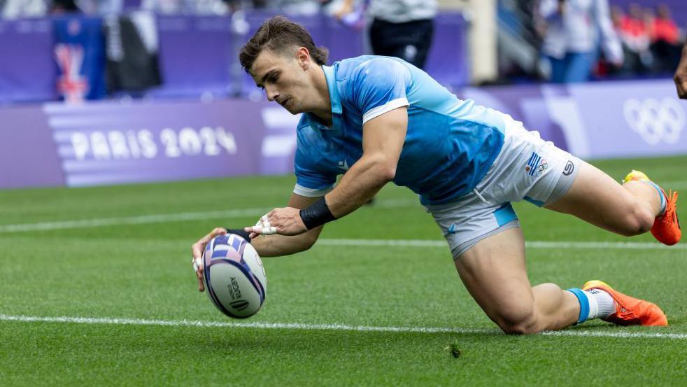 Juan Gonzalez is about to put the ball down behind the line after diving over for a try in a game for Uruguay