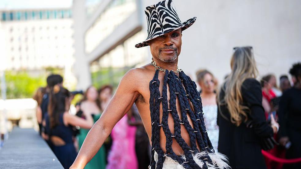 Billy Porter wearing a black roped top and white feathered skirt at the 2025 Baftas in London