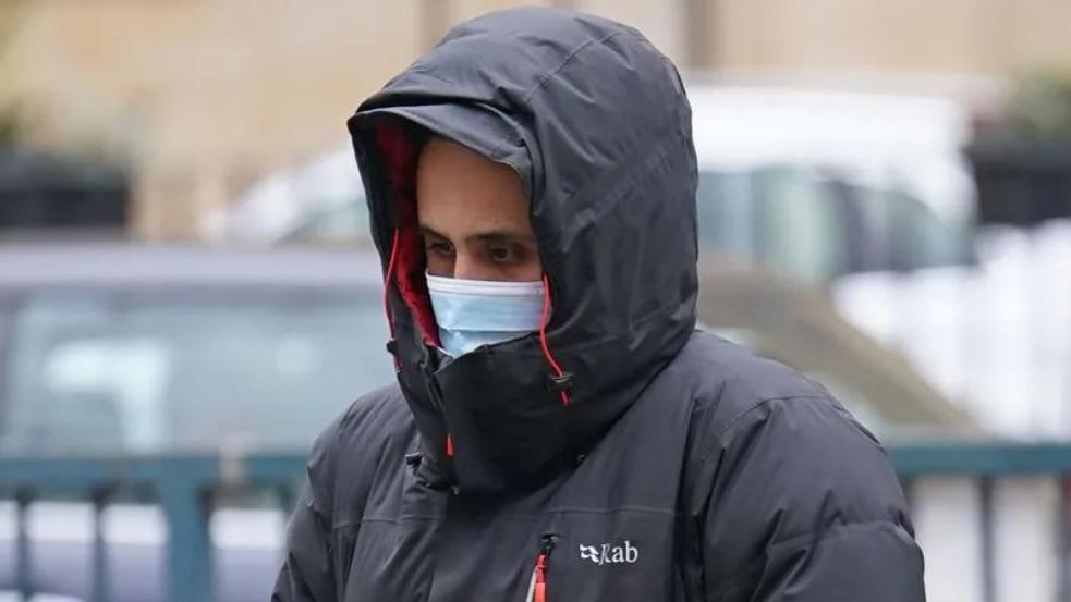 File image showing Muhammed Mustafa Darr attending a previous court hearing, wearing a black and red padded coat with the hood up, and a blue facemask