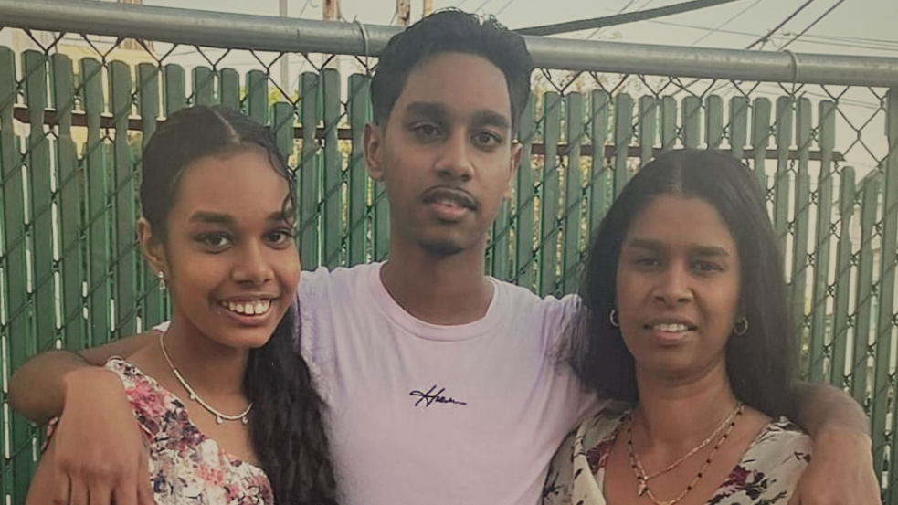 Shawn Seesahai with his arms around his sister and mother; they are all smiling at the camera