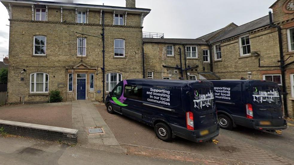 Stone two-storey office building with community payback vans in drive