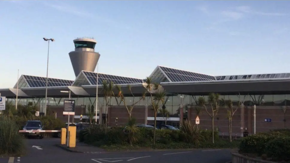 A photo of Jersey Airport's Departures terminal with the Air Traffic Control tower in the background and the car park in the foreground. 