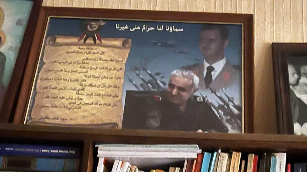 Jamil Hassan pictured in a composite photo in a frame, with Bashar al-Assad in the background 