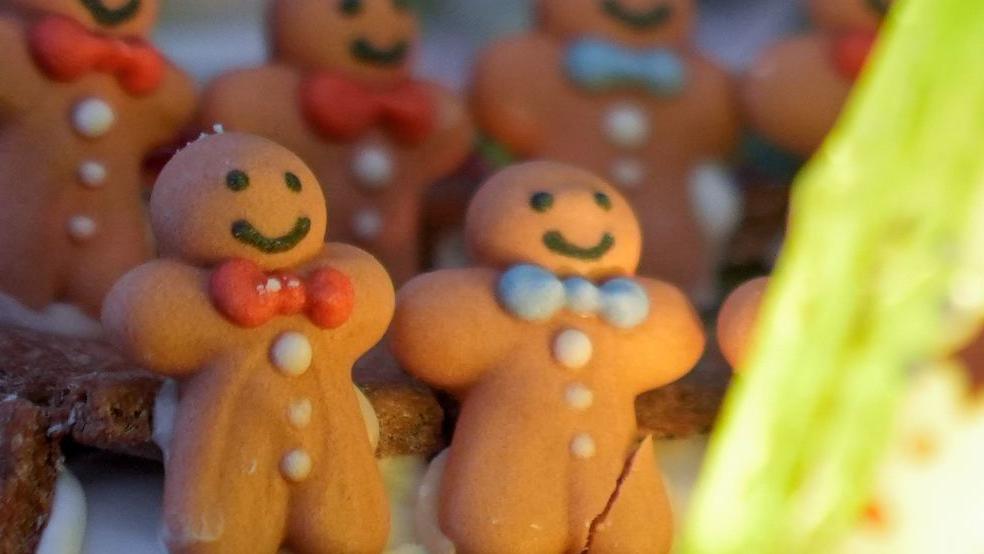 A close-up of two gingerbread people, one with a cracked leg.