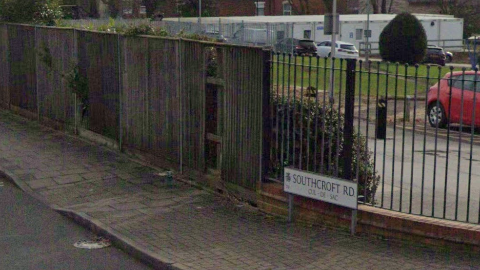 A street sign saying Southcroft Road, alongside a metal and wood fence