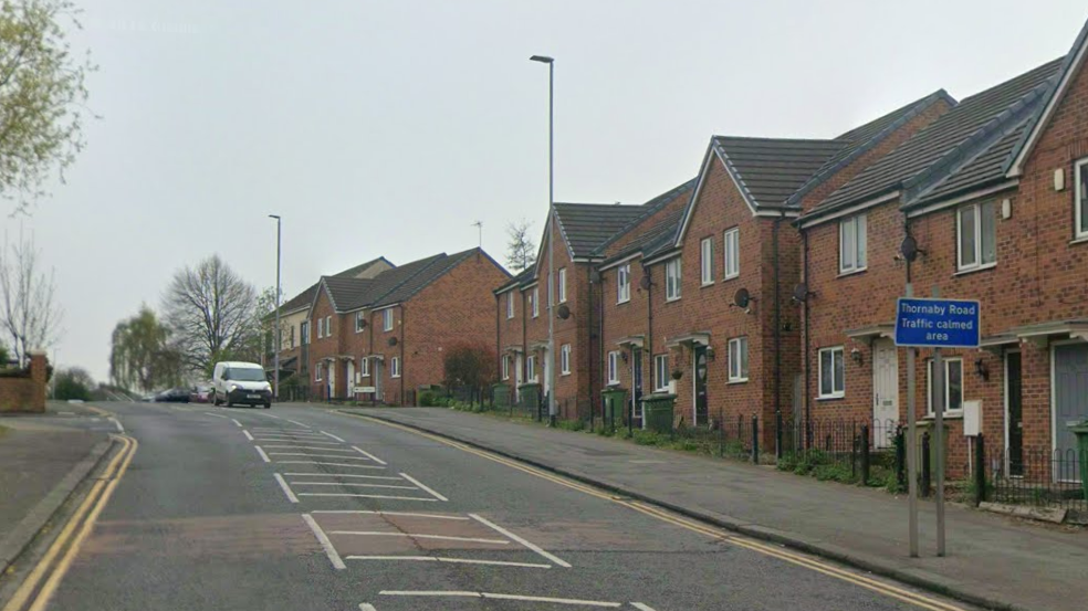 Thornaby Road is a residential street in Thornaby. It is a single-carriageway with one van travelling down it. There is a blue road sign reading 'Thornaby Road Traffic calmed area'. There are several terraced houses on the right side of the road.