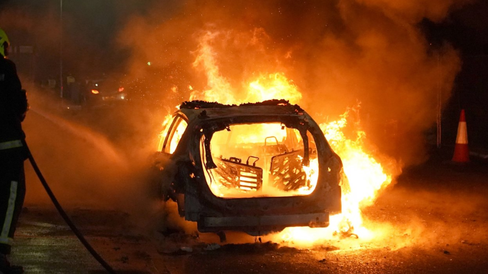 Firefighters tend to a burning police car as officers are deployed on the streets of Hartlepool following a violent protest.