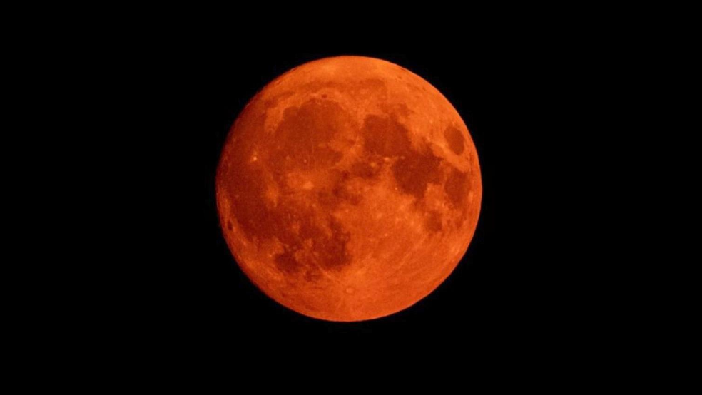 The full moon glowing red against a black background