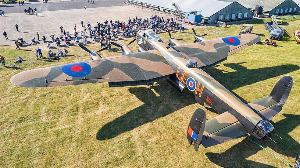 A large Lancaster bomber plane in front of crowds at an air show