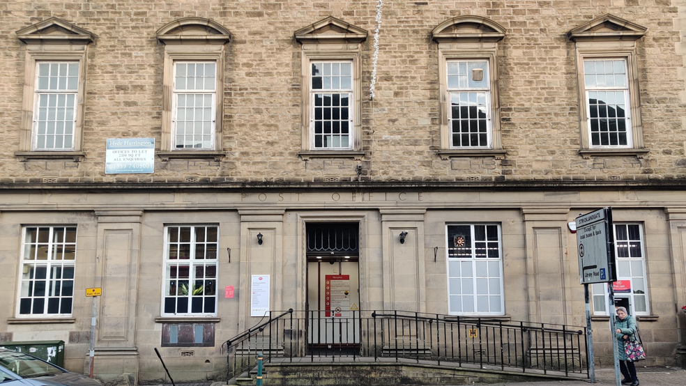 The Post Office branch in Kendal is a multi-storey white stone building with large white windows. The words: "Post Office" are engraved into the stone above the door.