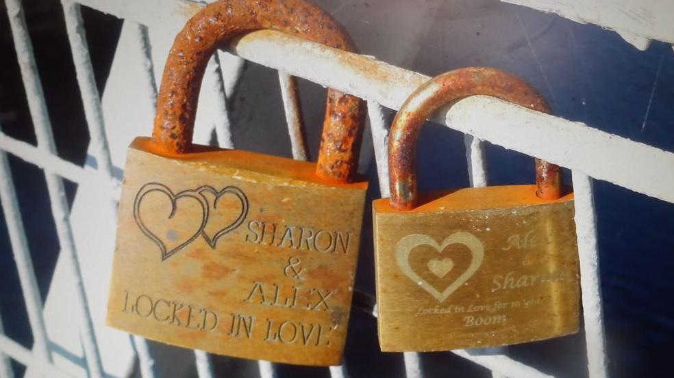 Two padlocks affixed to a the railings of a footbridge