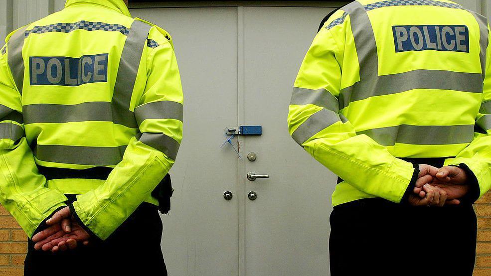 Two police officers standing with their backs to the camera