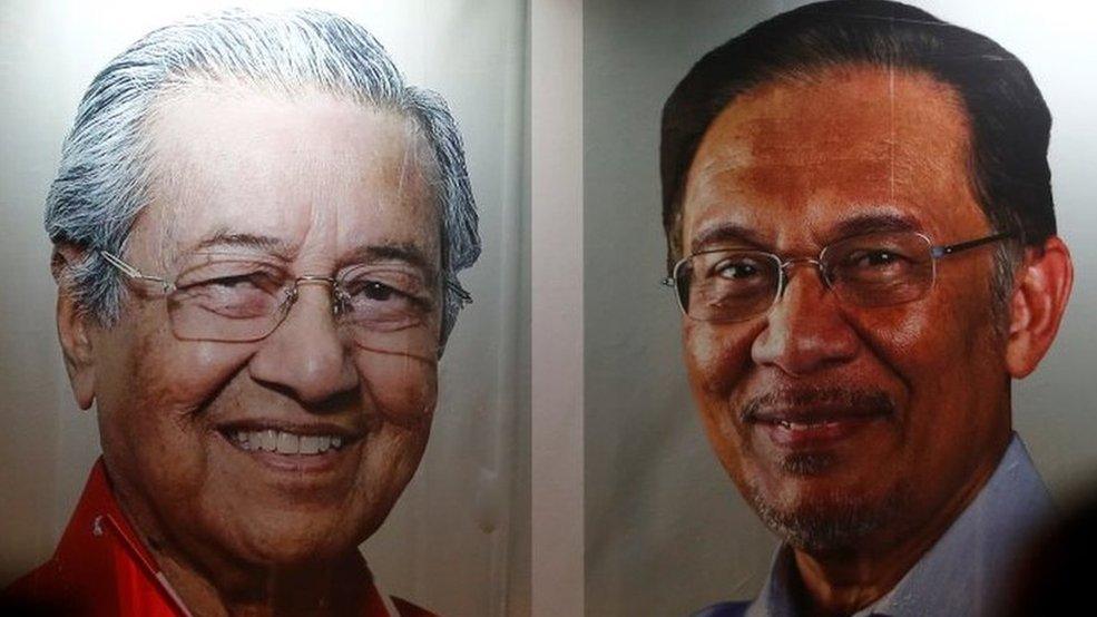 People pass posters of Malaysian Prime Minister Mahathir Mohammad and politician Anwar Ibrahim, who was granted a royal pardon, at a rally in Kuala Lumpur, Malaysia May 16, 2018.