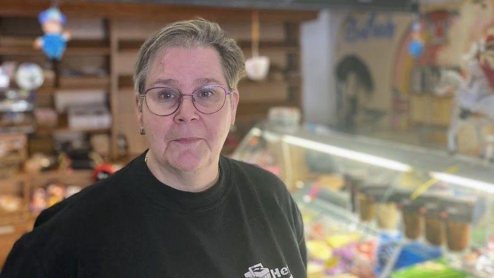Andrea, the owner of the local grocery store, standing inside her shop