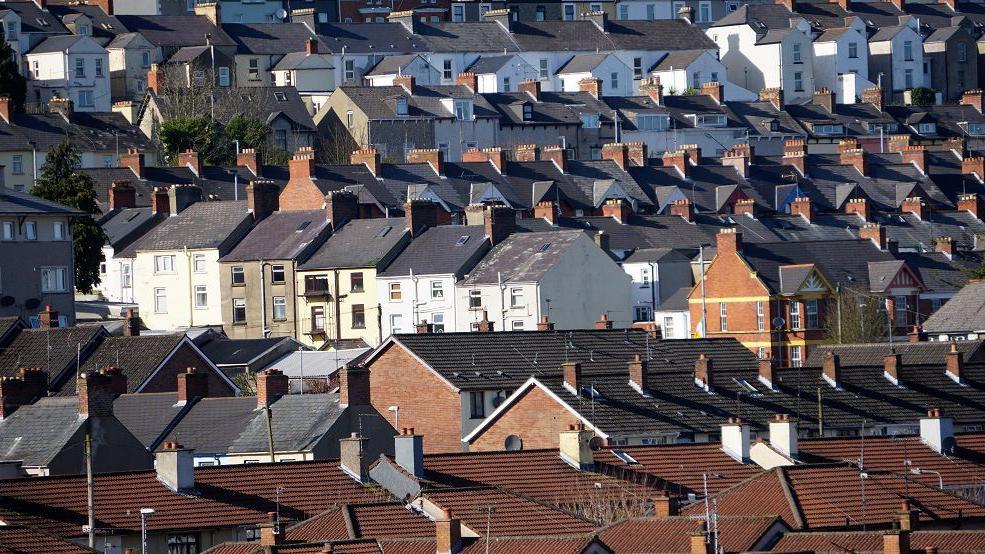 Row of houses in Londonderry, red brick with a mix of red and grey tiled roofs. 