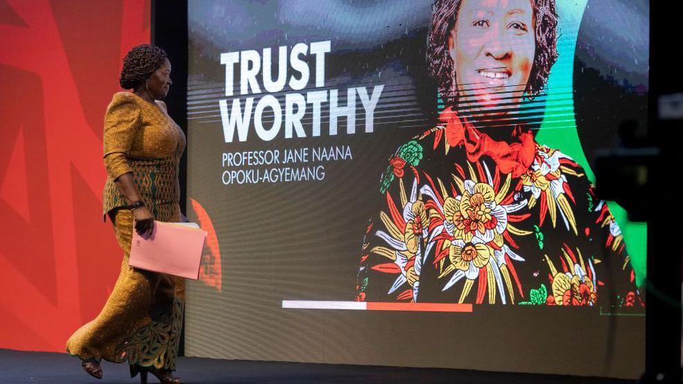 Naana Jane Opoku-Agyemang, running mate to John Mahama, walks off the stage after delivering a speech on 24 April 2024 in Accra, Ghana. Behind her is a screen with a photo of her and words 'Trust Worthy'