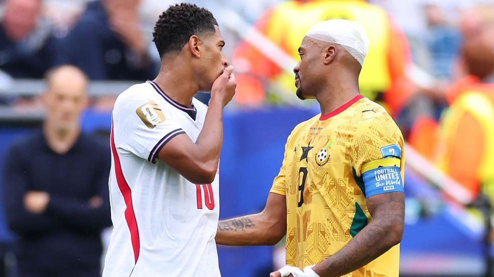 England's Jude Bellingham covers his mouth as he speaks with Ghana's Jordan Ayew