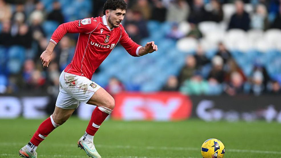 Liberato Cacace runs with ball during a game for Wrexham