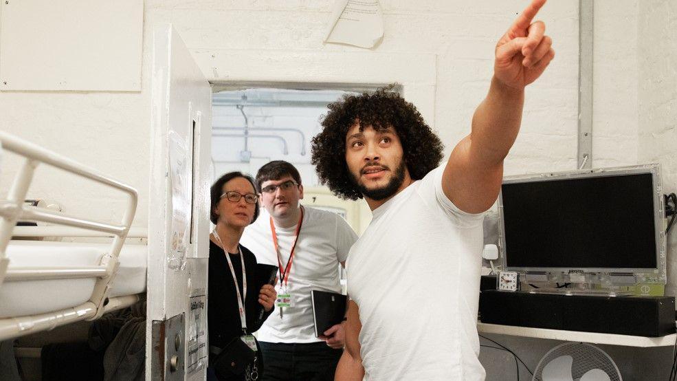 A prisoner talks to volunteer monitors in his cell