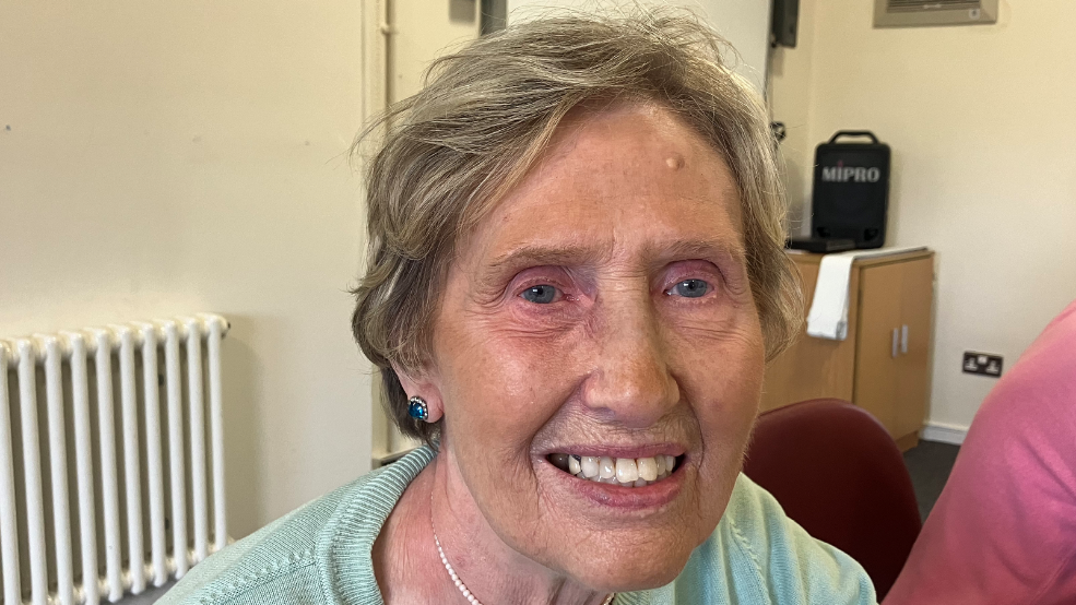 A woman in a green jumper smiling at the camera