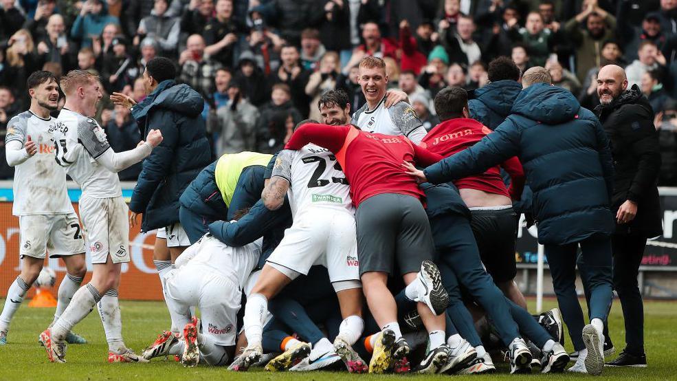 Swansea players and staff celebrate during their win over Cardiff in March