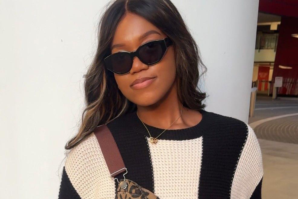 A woman with dark hair in sunglasses, a black and white striped jumper and leopard-print dungarees