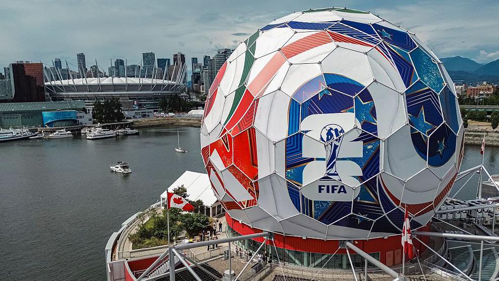 An aerial shot of circular building that has been covered in Adidas decals and posters to make it look like the World Cup match ball. In the background you can see BC Place, one of the World Cup venues.