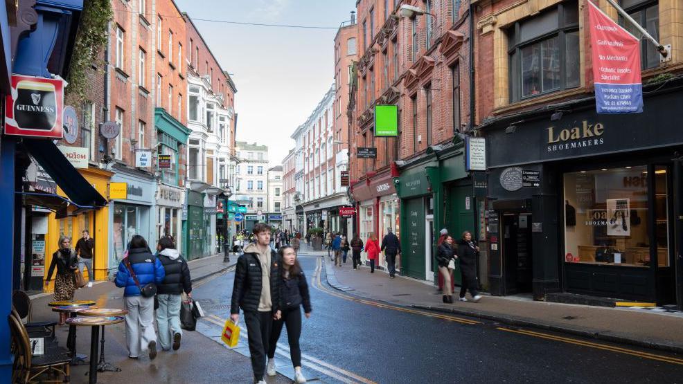 Shoppers on Wicklow Street in Dublin, Ireland, on Thursday, March 28, 2024. The shops are colourful and a young man and girl walk along the street.