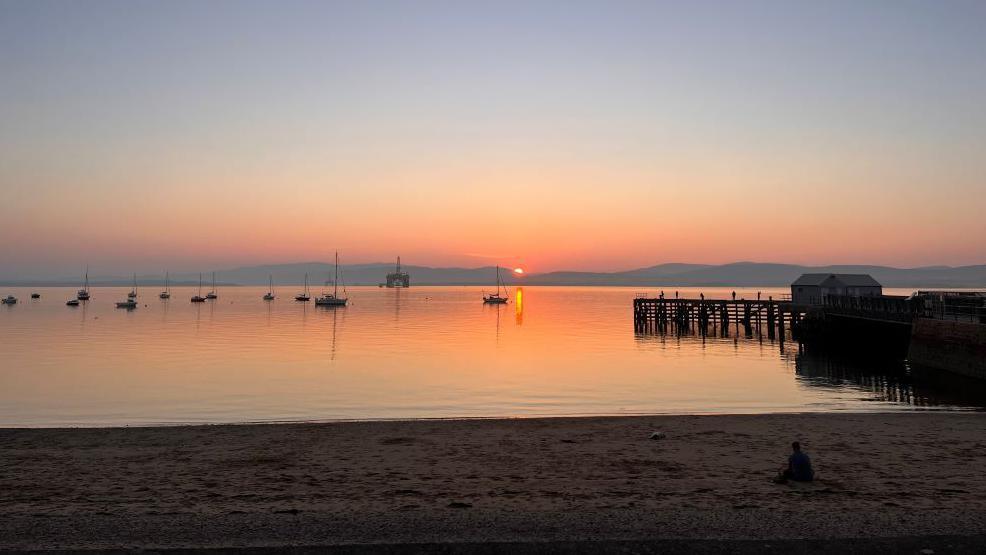 Sunset on the Cromarty Firth with boats and an oil rig on the water