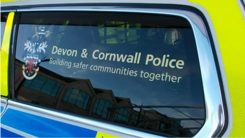 The window of a police vehicle which has a 'Devon & Cornwall Police Building safer communities together' sticker on it with the logo to the left.