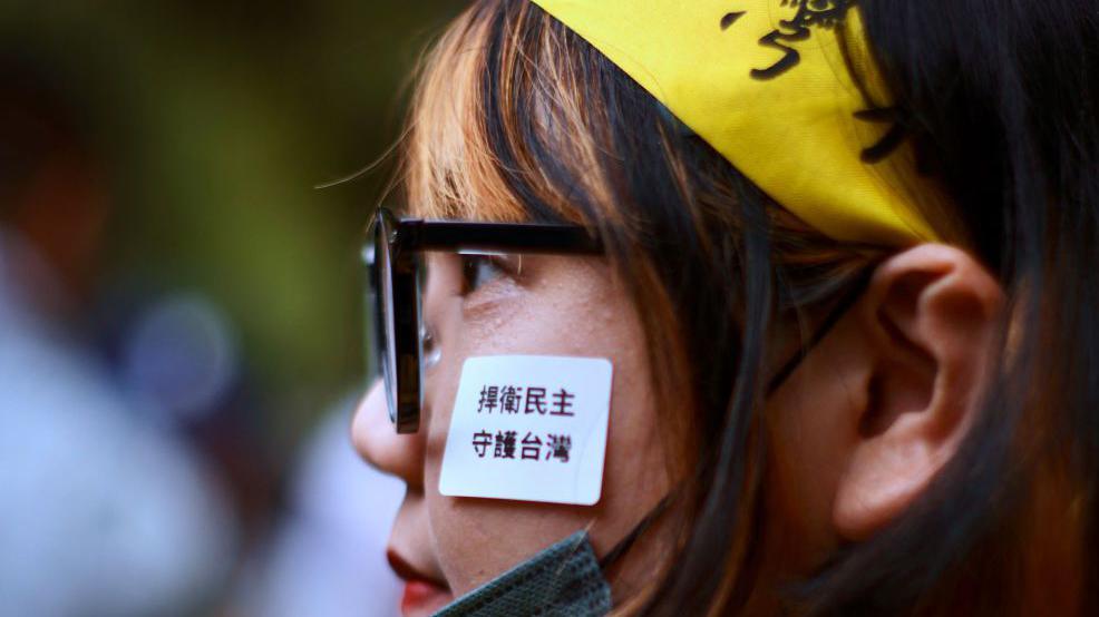 A supporter of ruling Democrats Progressive Party (DPP) puts a sticker on her face reading "Defense Democracy, stand guard Taiwan" during a Parliament reform bill voting at the Parliament on 24 May, 2024.