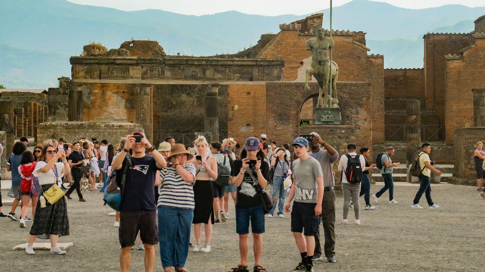 Tourists crowd the the Archaeological Park of Pompeii, walking around and taking pictures.