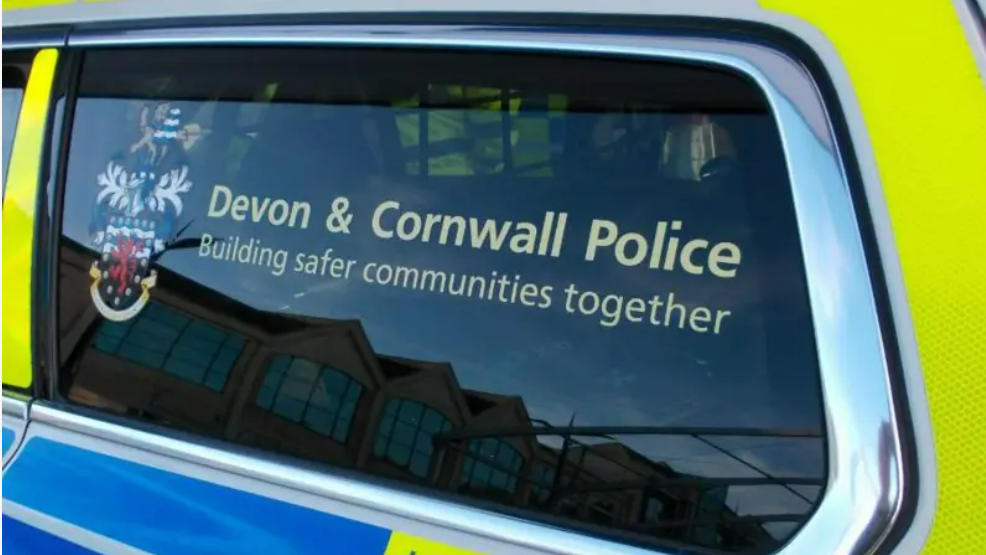 The window of a police vehicle which has a 'Devon & Cornwall Police Building safer communities together' sticker on it with the logo to the left.