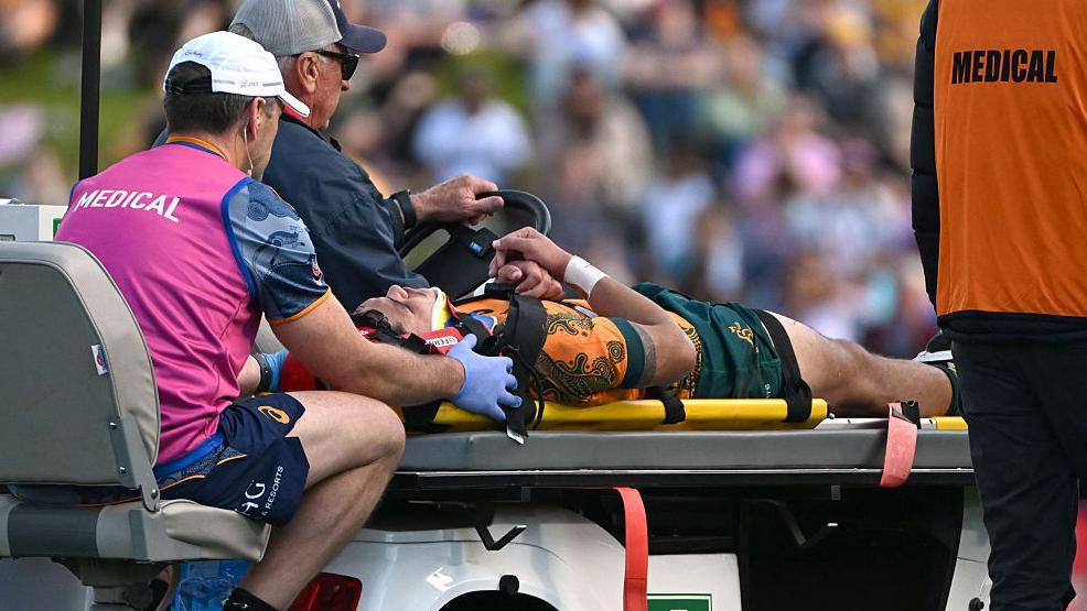 Noah Lolesio is carted off the pitch against Fiji