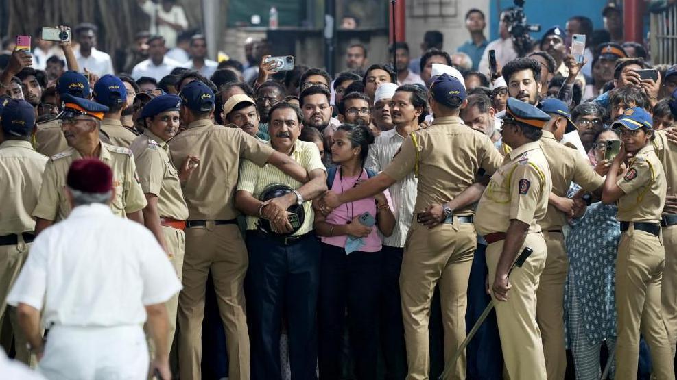 Police officers control a crowd as they gather on the day of the funeral of the former chairman of Tata Group Ratan Tata at a crematorium ground in Mumbai, India, October 10, 2024.