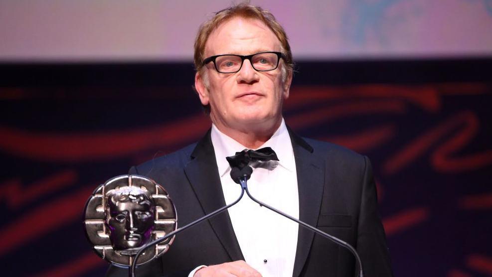 Mark Lewis Jones accepts the Siân Phillips Award on stage during the 2024 BAFTA Cymru awards 