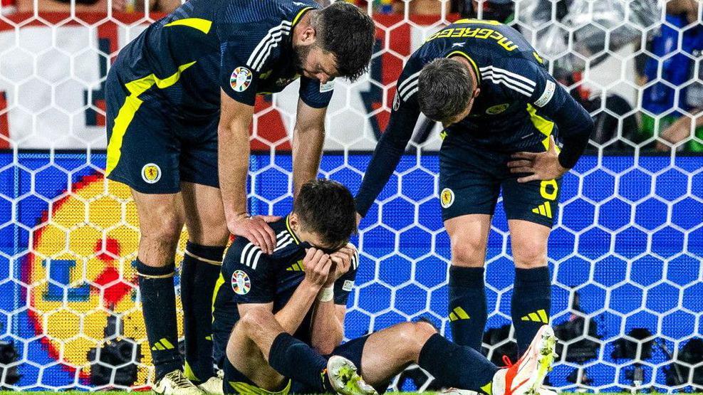 Kieran Tierney is consoled by Scotland team-mates Grant Hanley and Callum McGregor 