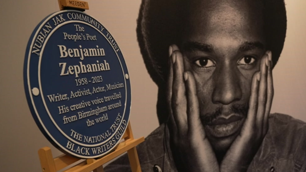 The plaque rests on a wooden frame with a black and white photo of Zephaniah as a younger man with his hands on face.