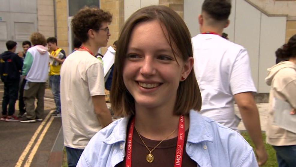 Michele Voncken. She has short brown hair and is looking to the side of the lens, smiling.