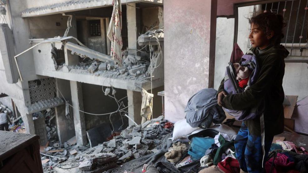 A girl searches for items at a house destroyed in strikes in the Shujaiya district in eastern Gaza City