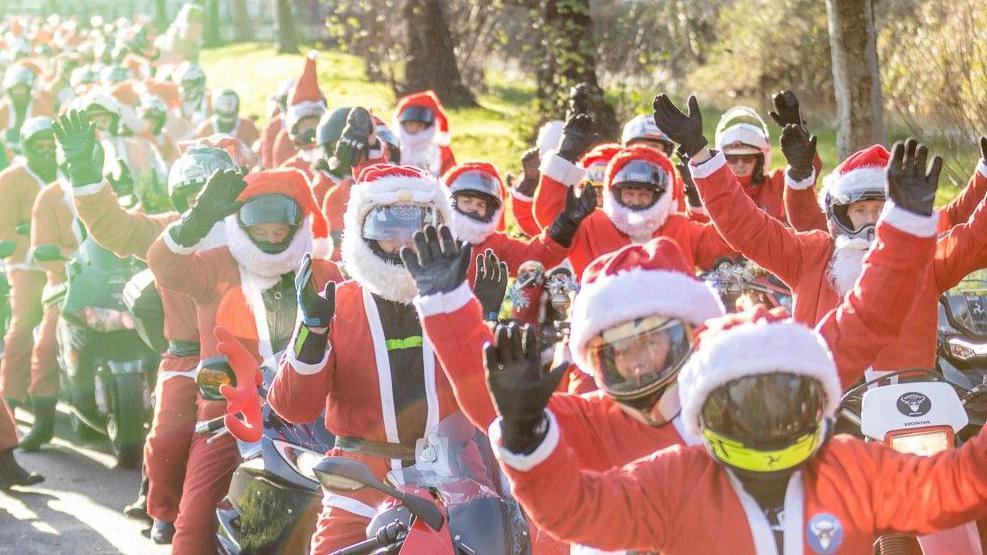 A long line of motorcyclists dressed in red Santa suits.
