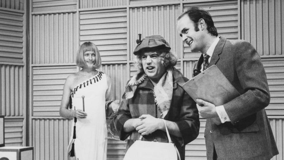 A black and white picture depicting comedians Graham Chapman, Terry Jones and John Cleese in the 'Take Your Pick' sketch from series 2 of the BBC television show Monty Python's Flying Circus