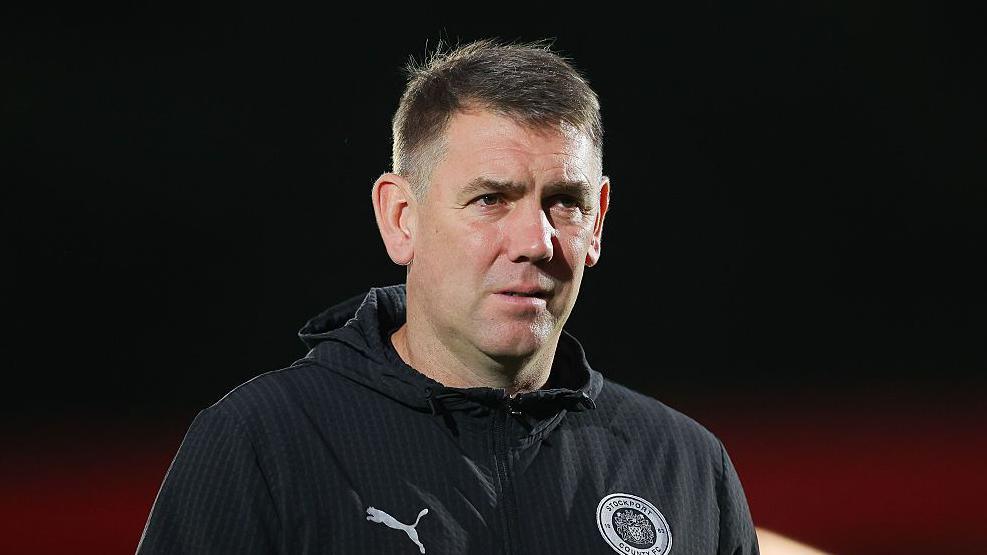 Manager Dave Challinor wears a serious expression on the touchline for Stockport County