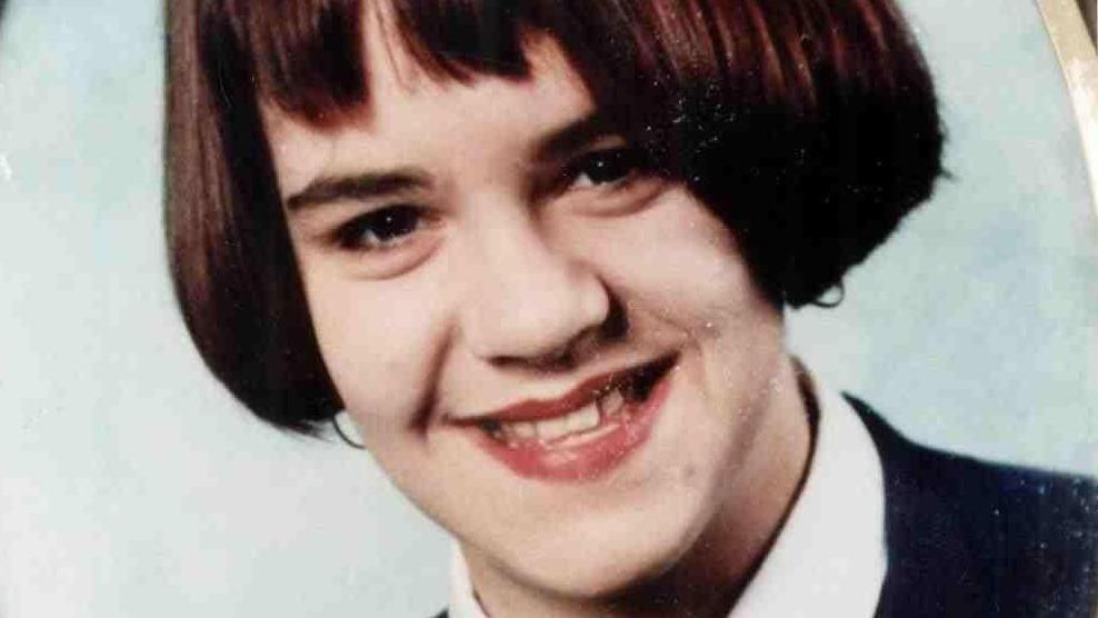 A photo from the early 1990s of schoolgirl Vicky. It looks like a school photo. She is wearing a school uniform. She has brown hair in a bob style and is smiling at the camera