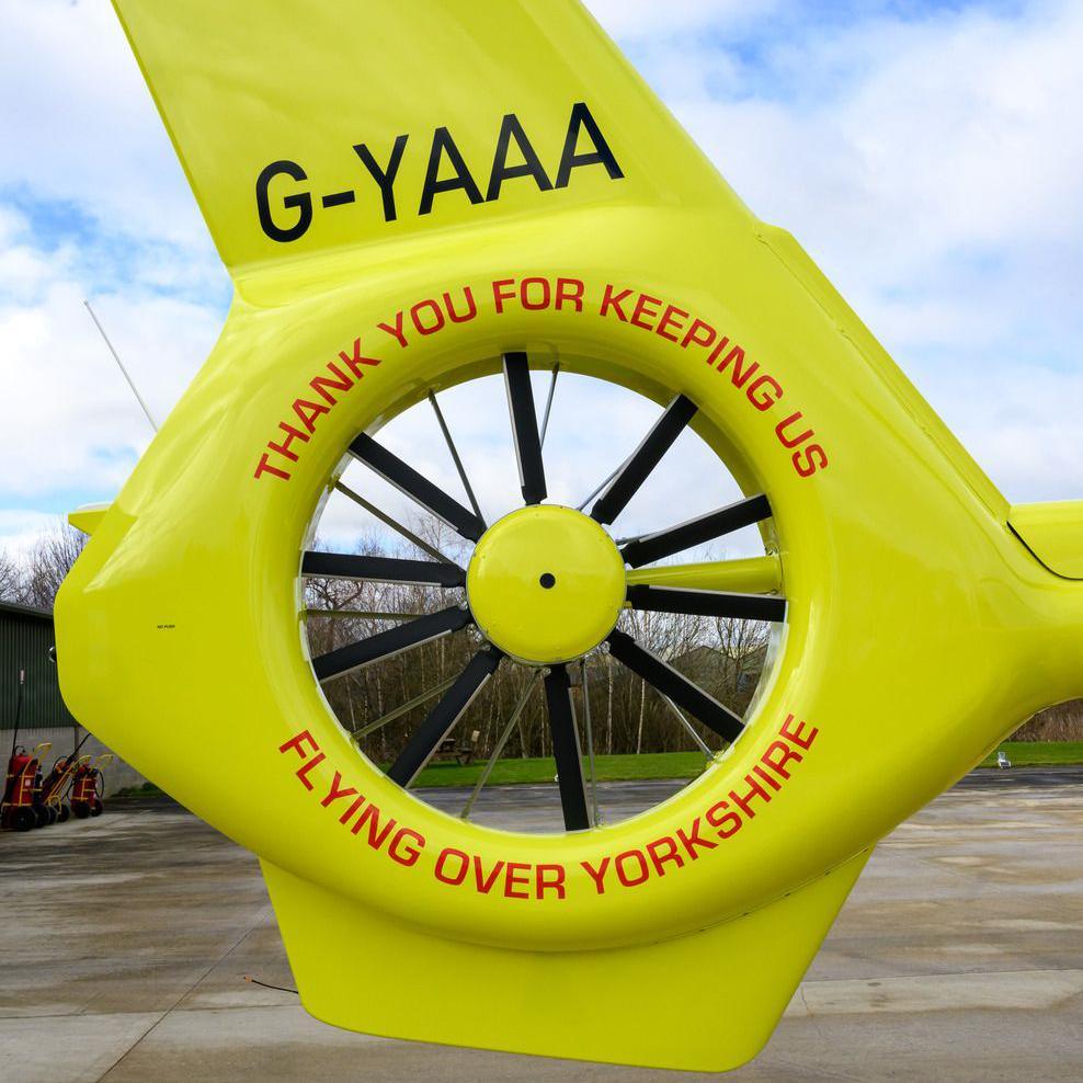 The tail bumper of one of the air ambulance helicopters. It is bright yellow. Painted on in red lettering is "Thank you for keeping us flying over Yorkshire". 