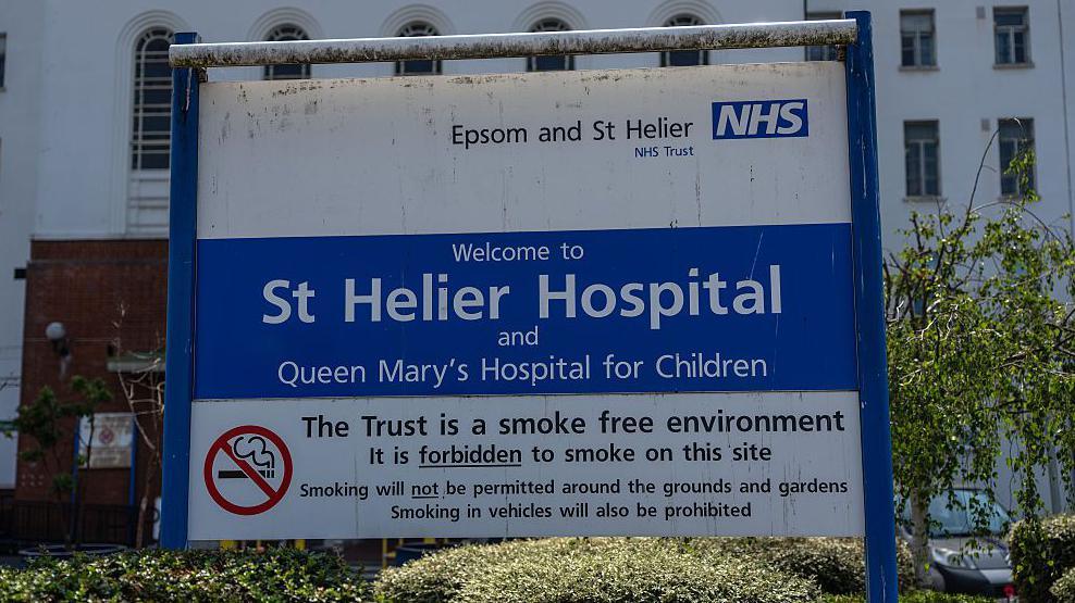 Sign outside St Helier Hospital displaying the hospital name and NHS branding
